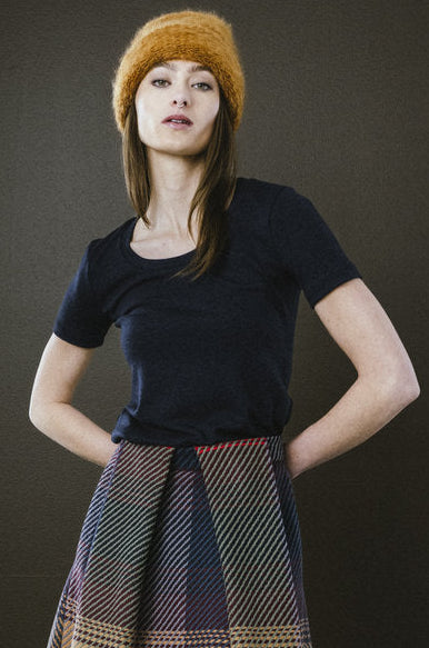 A person wearing a black fitted short sleeve t-shirt and a multicolored skirt with a low neckline.